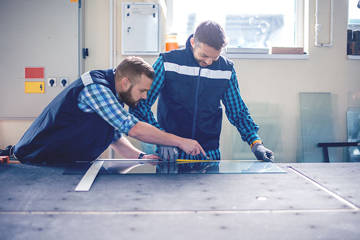 2 workers cutting glass in a shop