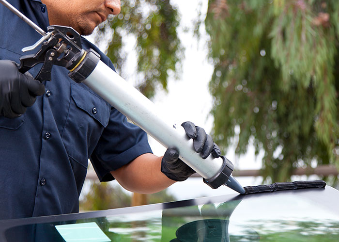 auto glass professional adding sealant to windshield